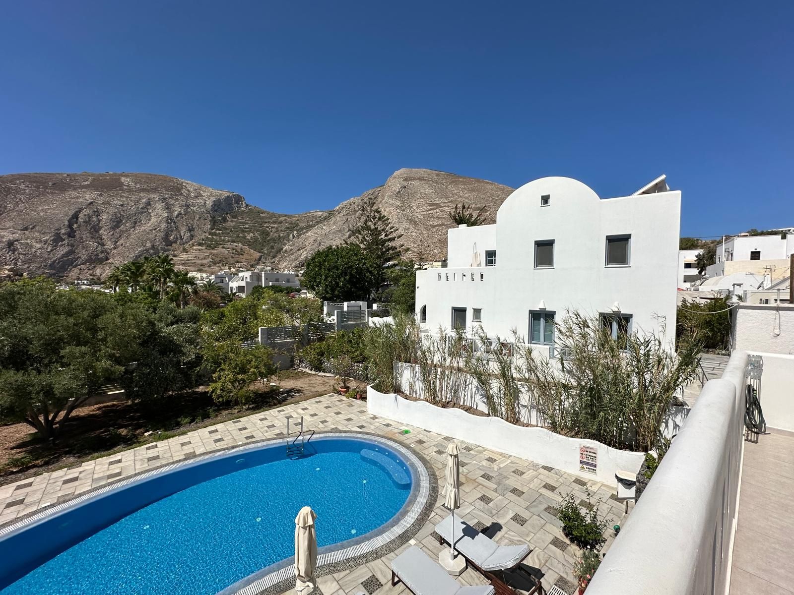 The shared pool and garden at Felicity Kamari Villas, with Mesa Vouno rising behind the village